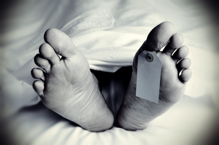 closeup of the feet of a dead body covered with a sheet, with a blank tag tied on the big toe of his left foot, in monochrome, with a vignette added